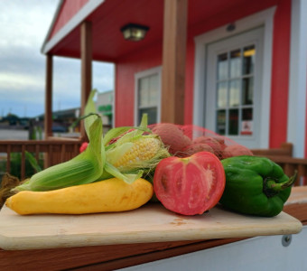Variety of produce offer at Griggs Bros. Farms including red slicing tomatoes, bell peppers, new potatoes, yellow squash, and sweet corn
